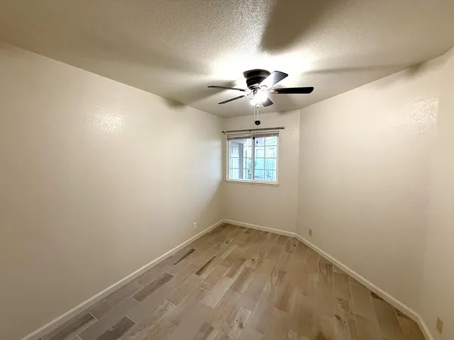an empty room with a chandelier fan and windows