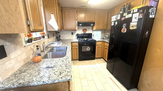 a kitchen with stainless steel appliances granite countertop a refrigerator stove and sink