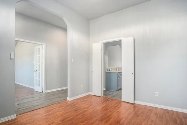 a view of an empty room with wooden floor & closet