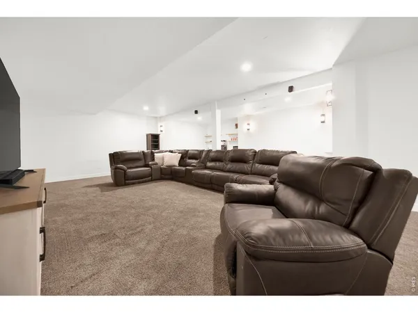 a living room with couches and kitchen view with wooden floor