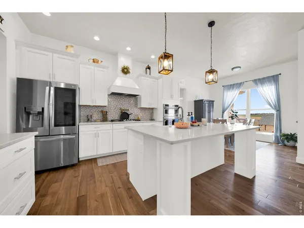a kitchen with stainless steel appliances kitchen island a refrigerator and a wooden floors
