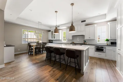 a kitchen with stainless steel appliances granite countertop wooden floors stove and white cabinets