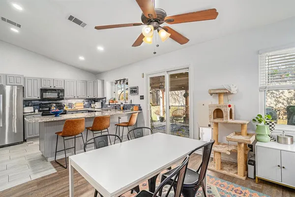 a dining room with stainless steel appliances kitchen island granite countertop a dining table chairs and a refrigerator