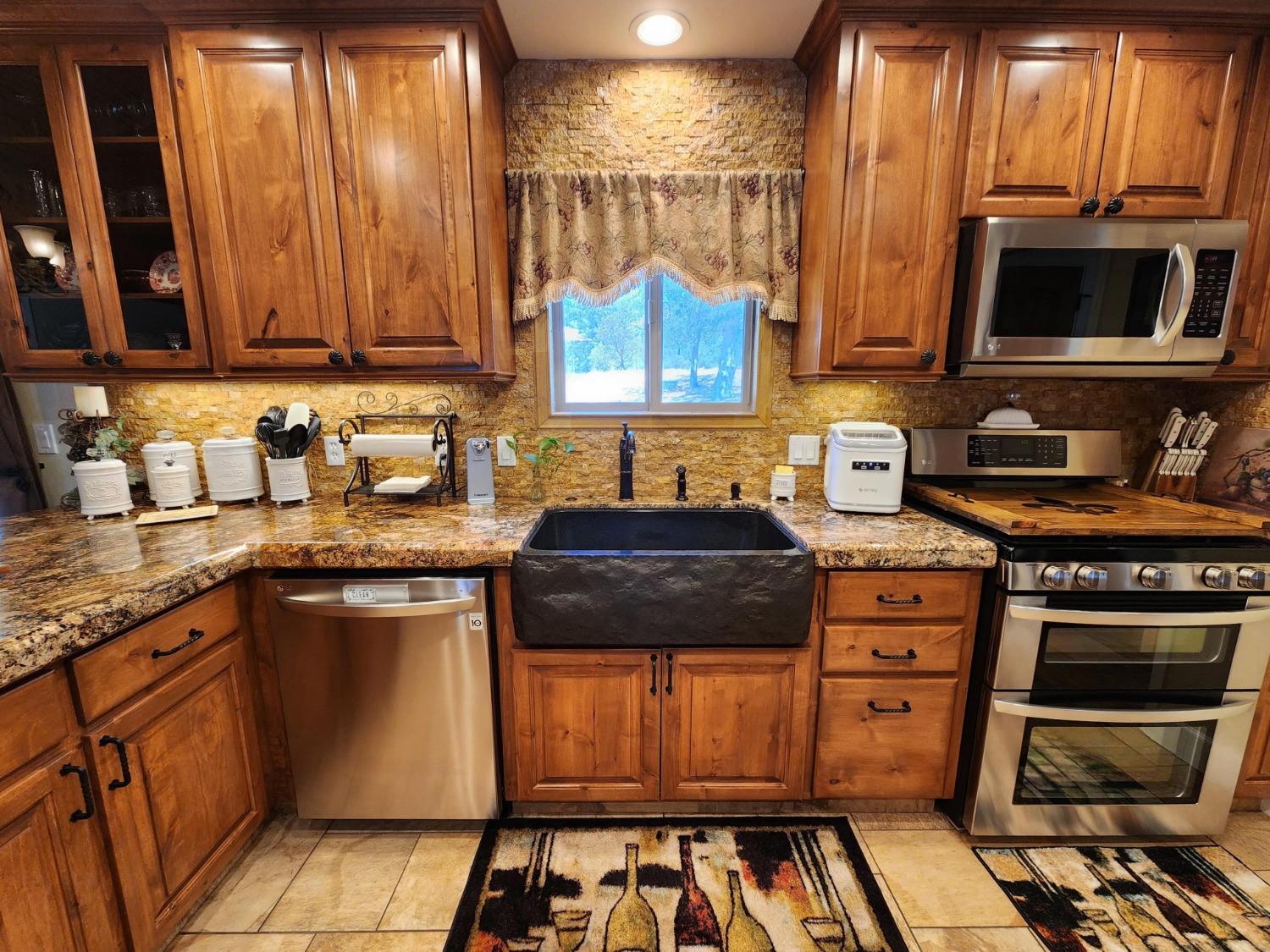28903 Limestone Circle Coarsegold, CA 93614 - Photo 11 of 59 a kitchen with stainless steel appliances granite countertop a stove a sink and a microwave