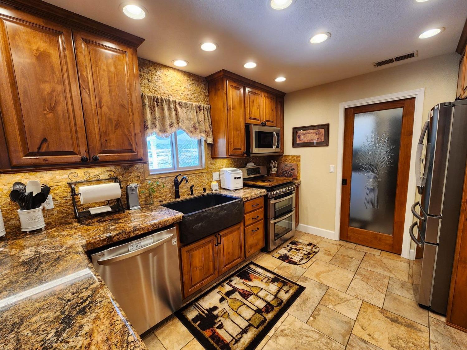28903 Limestone Circle Coarsegold, CA 93614 - Photo 14 of 59 a kitchen with stainless steel appliances granite countertop a stove top oven a sink and a refrigerator
