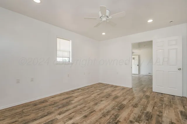 a view of empty room with wooden floor and ceiling fan