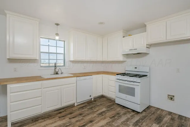 a kitchen with granite countertop a sink cabinets and wooden floor