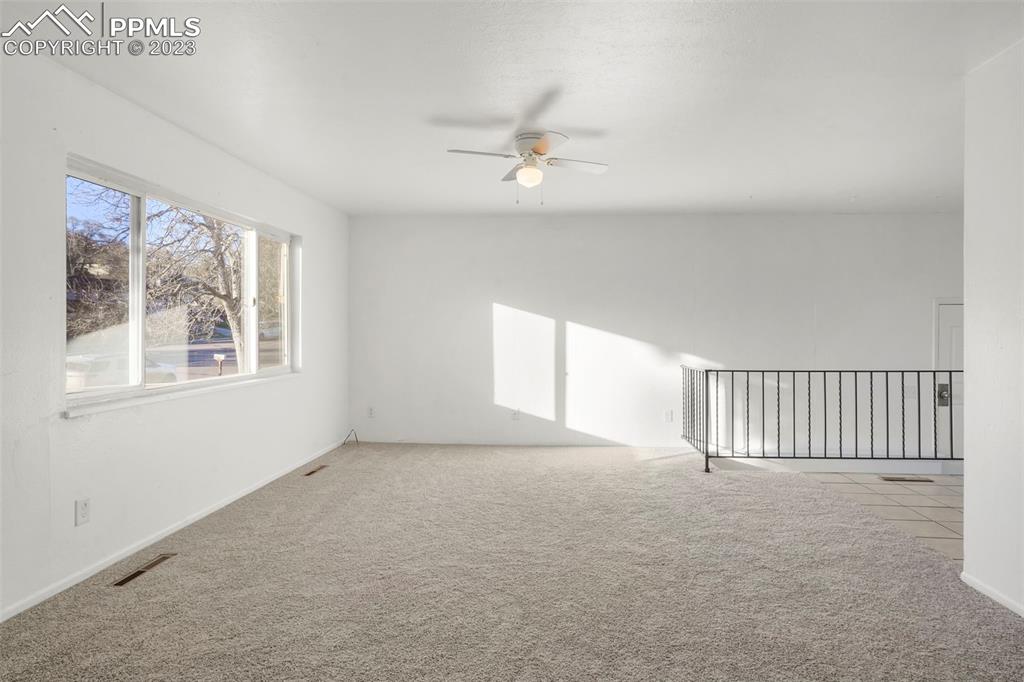 1159 Peterson Road Colorado Springs, CO 80915 - Photo 2 of 22 an empty room with windows and ceiling fan
