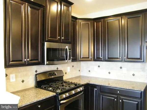 a kitchen with granite countertop a refrigerator stove and sink