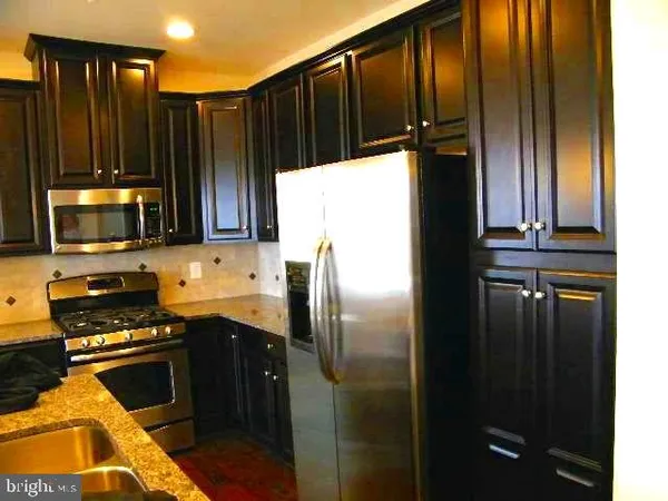 a kitchen with stainless steel appliances granite countertop a refrigerator and a stove top oven