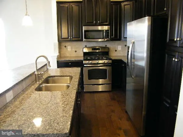 a kitchen with granite countertop a refrigerator stove and microwave