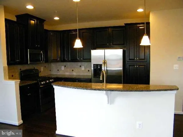 a kitchen with stainless steel appliances kitchen island granite countertop a refrigerator a sink and a stove