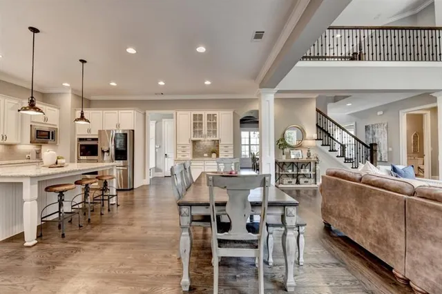 a kitchen with a stove a sink a kitchen island with chairs and wooden floor