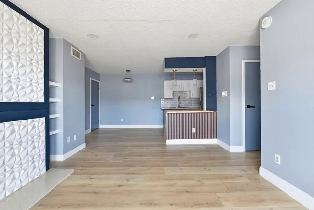 a view of a hallway with wooden floor and a living room
