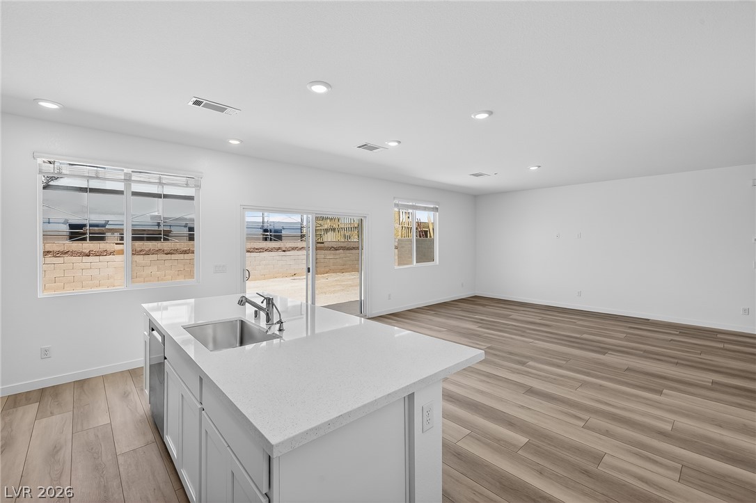 347 Sam Way Mesquite, NV 89027 - Photo 8 of 32 A well-lit kitchen island with a sink flows into a spacious living area featuring wood flooring and ample natural light.