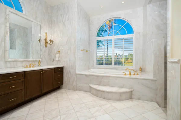 a spacious bathroom with a granite countertop sink a large mirror and a bathtub next to a window