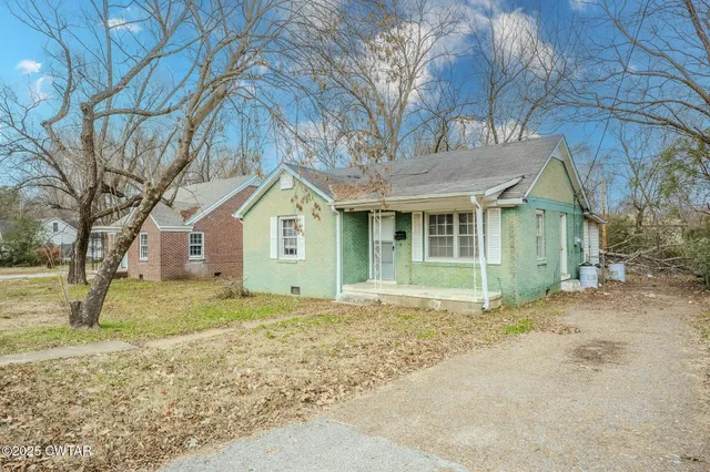 a view of a yard in front of a house with a large tree