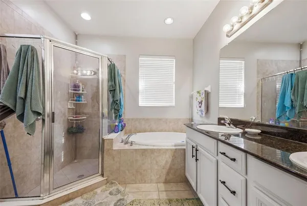 a bathroom with a granite countertop tub sink and mirror
