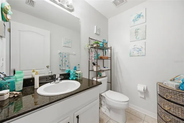 a bathroom with a granite countertop sink a toilet a mirror and shower