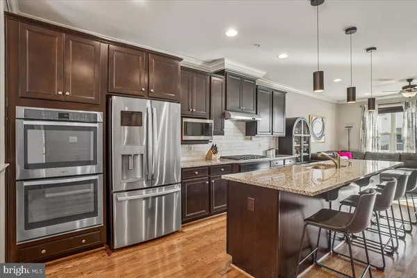 a kitchen with stainless steel appliances granite countertop a table chairs and a wooden cabinets