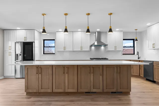 a view of a kitchen with kitchen island stainless steel appliances wooden floor and a sink