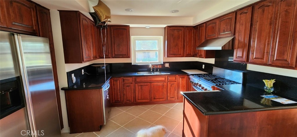 520 West Raymond Street Compton, CA 90220 - Photo 24 of 31 a kitchen with stainless steel appliances granite countertop a refrigerator a stove and a sink with wooden cabinets