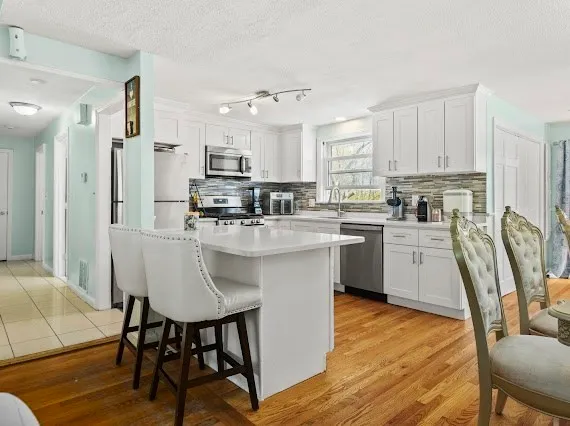 a kitchen with stainless steel appliances granite countertop a table chairs refrigerator a sink dishwasher and microwave with wooden floor