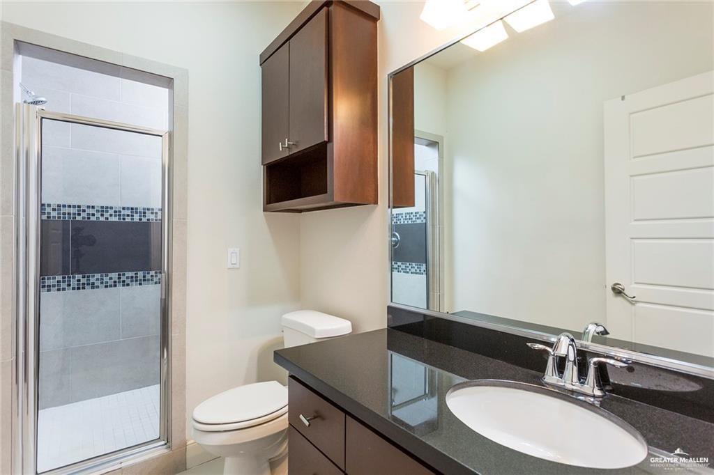 3016 South L Street, Unit 2 McAllen, TX 78503 - Photo 6 of 10 a bathroom with a granite countertop sink toilet a mirror a vanity and shower