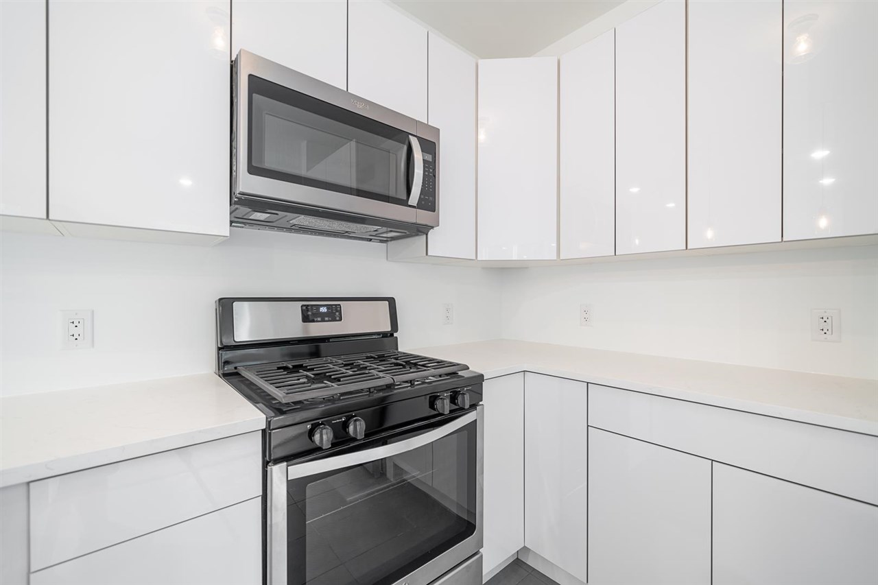 8621 River Road, Unit 6D North Bergen, NJ 07047 - Photo 9 of 34 a kitchen with stainless steel appliances granite countertop white cabinets and a stove top oven