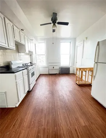 a kitchen with stainless steel appliances a stove top oven a sink a refrigerator wooden floor and cabinets