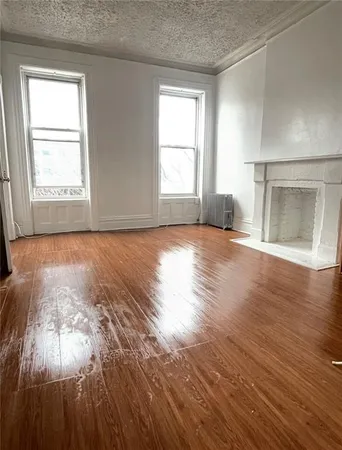 an empty room with wooden floor cabinet and windows