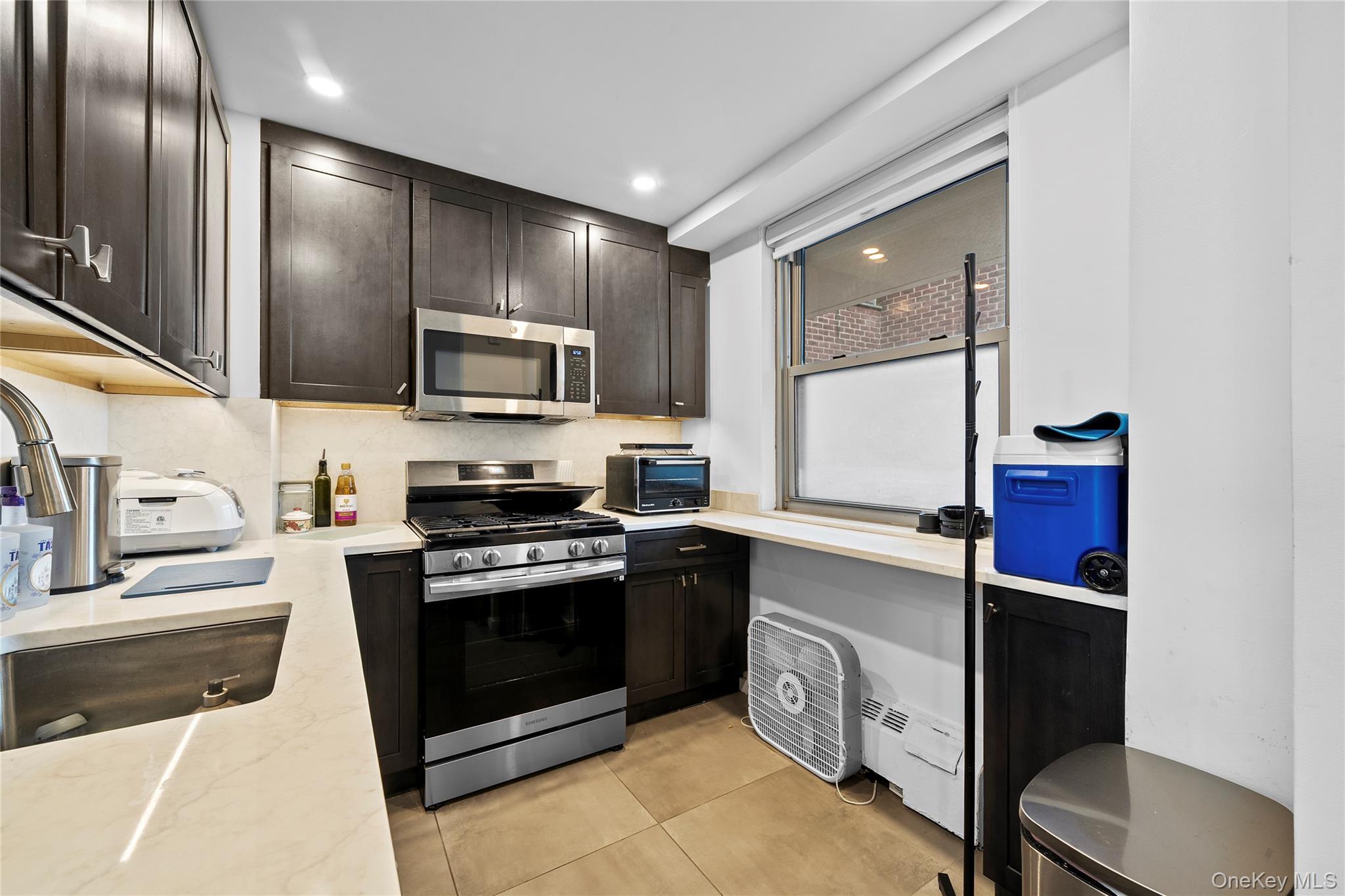 61-25 97th Street, Unit 12M Queens, NY 11374 - Photo 5 of 24 a kitchen with stainless steel appliances granite countertop a stove a sink and a microwave