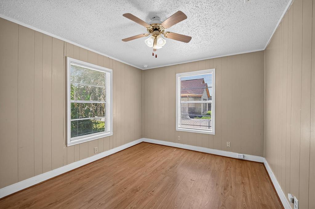 4450 Percy Street Lancaster, TX 75134 - Photo 11 of 18 Room featuring wood-finish flooring, two windows with blinds, a ceiling fan with integrated lighting, and paneling walls