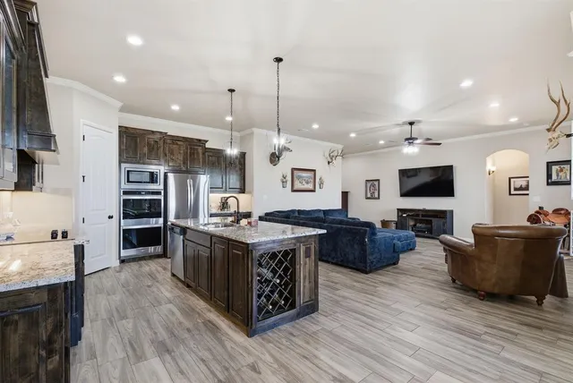 a large kitchen with stainless steel appliances granite countertop a stove and a wooden floors