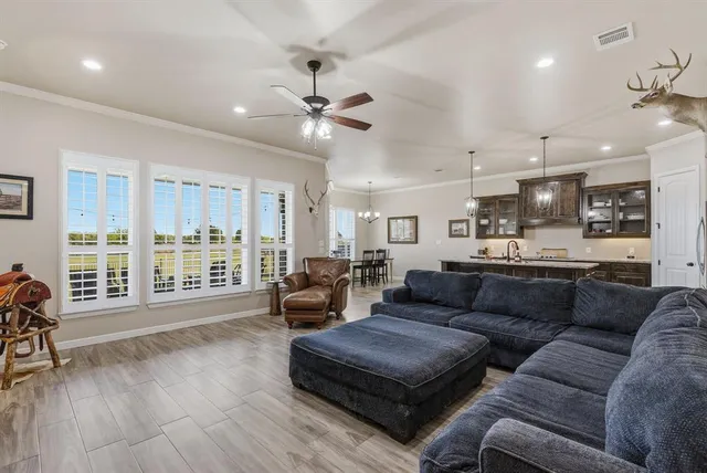 a living room with furniture and a large window with kitchen view