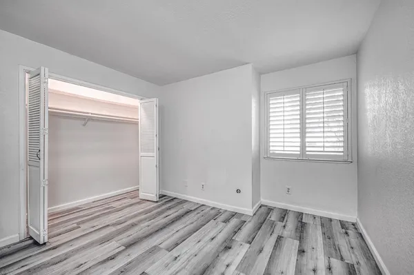 a view of empty room with wooden floor and fan
