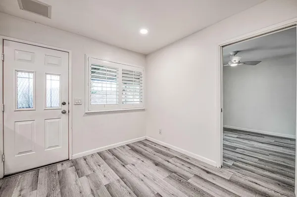 a view of an empty room with wooden floor and window