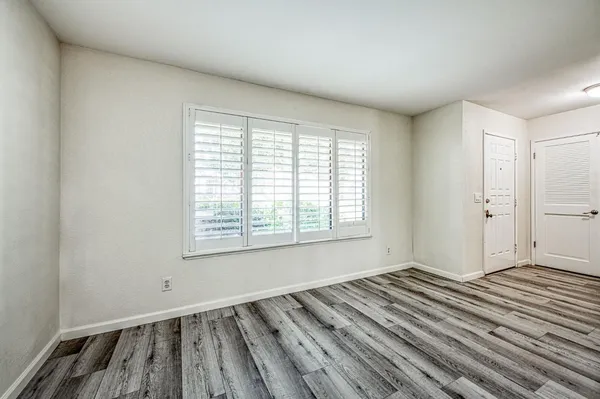 an empty room with wooden floor and windows