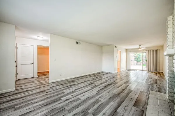an empty room with wooden floor fireplace and windows