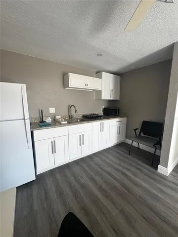 a living room with kitchen and a chandelier