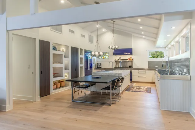 a dining hall with stainless steel appliances kitchen island granite countertop a refrigerator and a stove top oven