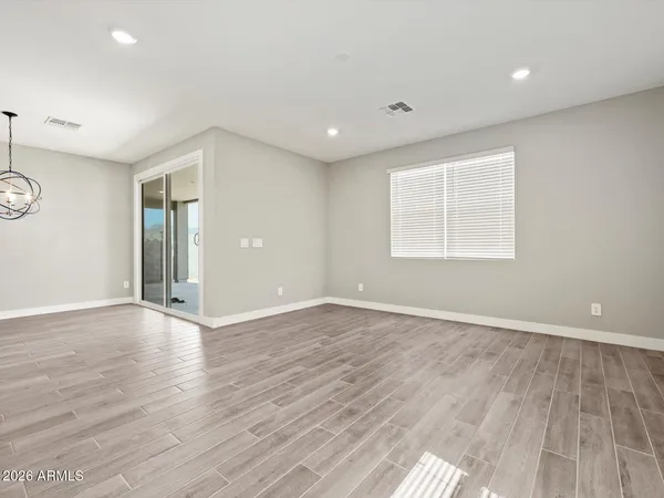 a view of an empty room with wooden floor and window