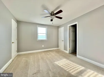 a view of an empty room with window and a ceiling fan