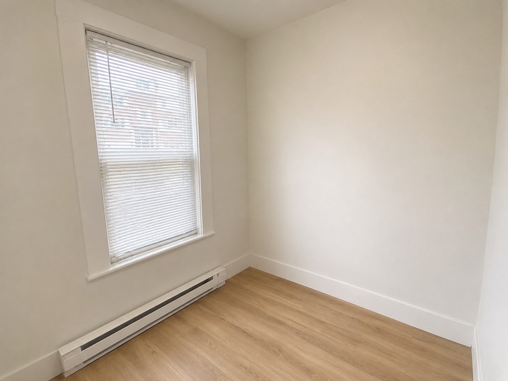 568 Main Street, Unit 3 Woburn, MA 01801 - Photo 5 of 8 an empty room with wooden floor and windows