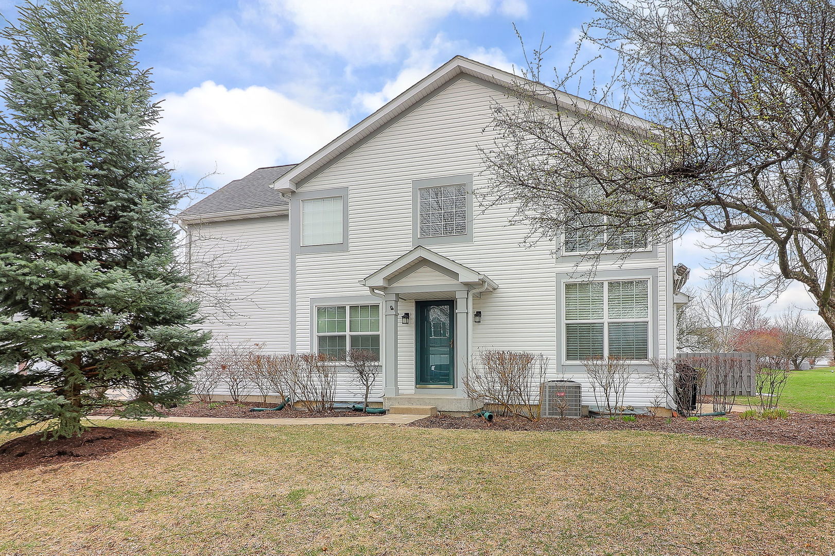 a front view of a house with a garden and trees