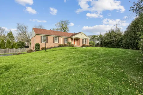 a view of a house with a big yard and large trees