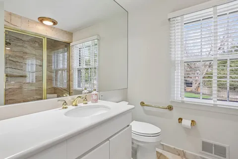 a bathroom with a sink a toilet and a large window