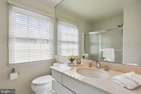 a bathroom with a granite countertop sink toilet a large mirror and a window