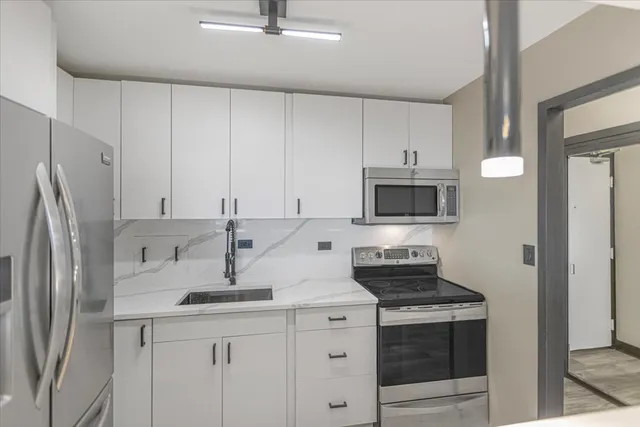 a kitchen with stainless steel appliances granite countertop a sink stove and refrigerator