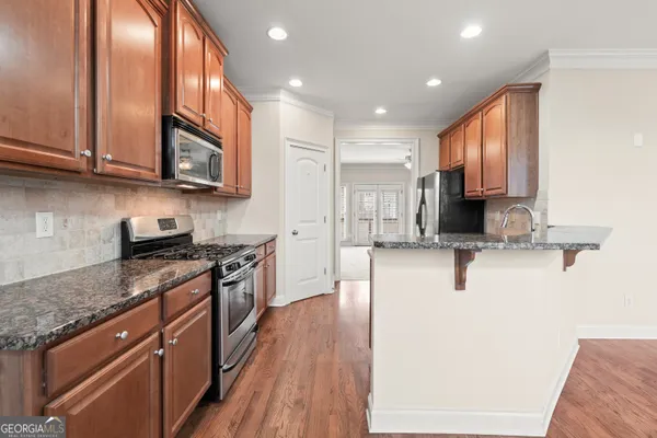 a large kitchen with stainless steel appliances granite countertop a stove a sink dishwasher and a microwave oven with wooden floor